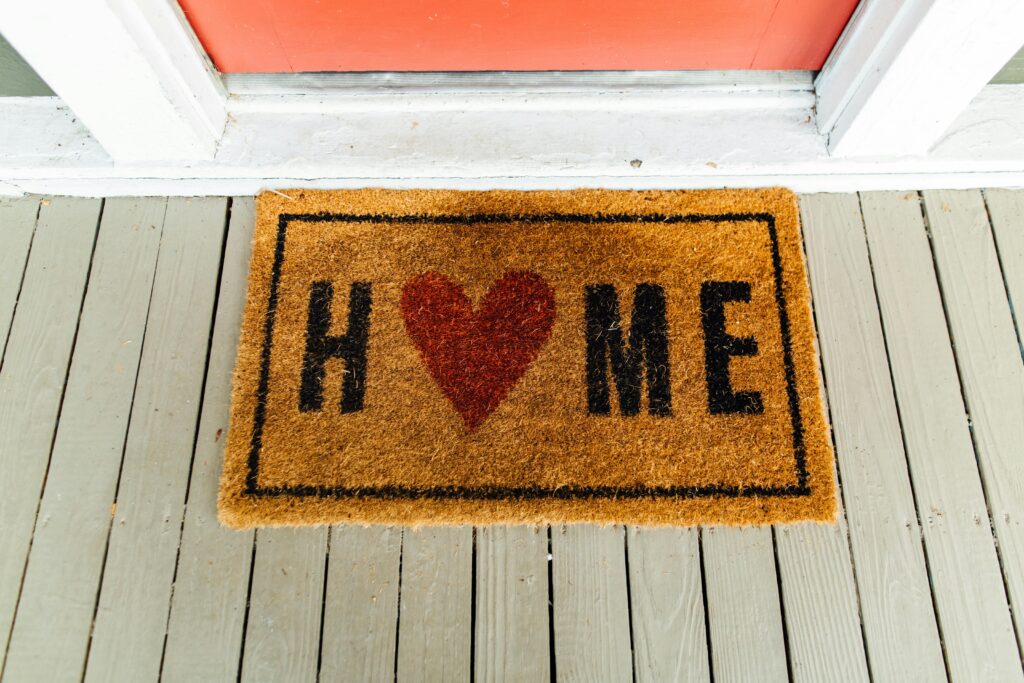 pexels-photo-2949992-2949992 Doormat with 'Home' written and heart symbol on wooden porch.